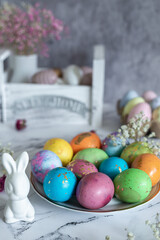 Beautiful multi -colored decorated Easter eggs and a cute white Easter rabbit on a white mromoic background. Ideas for decoration for the holiday