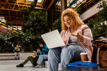 Portrait of female student siting in campus using laptop.