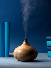 Wooden vaporizer with vapor of natural oils, with different ranges of blue, on the gray table in the living room