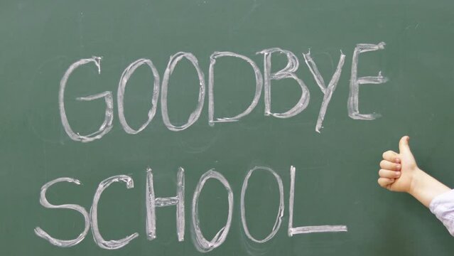 words goodbye school written on school chalkboard with white and woman hand finishing to write.kid child preschooler little small hands showing like thumbs up in a corner.last day of school bye 4k