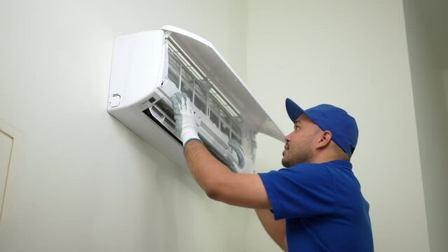 Technician in blue uniform check and cleaning filters of air conditioner. Air condition maintenance service. Home services concept.