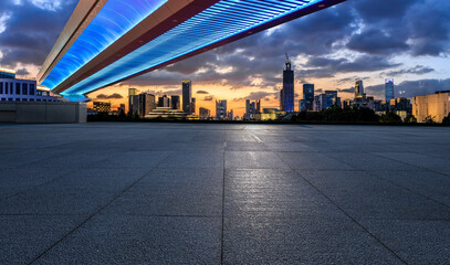 Empty square floor and pedestrian bridge with city skyline at sunset in Ningbo, Zhejiang Province, China.