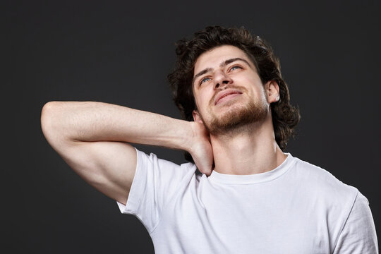 young man with neck pain on dark gray background