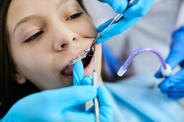 Close up of dentist adjusts teenage girl's dental braces at dentist's office.