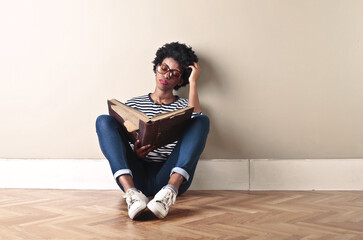bored young woman reads a book sitting on the floor