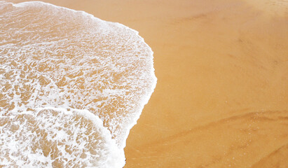 Aerial view of the waves with foam on the sandy ocean shore. Beautiful texture background for tourism and design. Tropical seashore