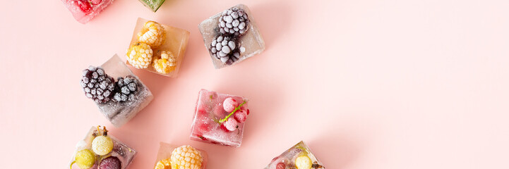 Frozen ice cubes with various fruits banner, blackberries and raspberries, gooseberries and currants, blueberries and mint, top view