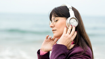 Woman with wireless headphones feeling the music. Wireless headphones connected to the smartphone....