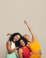 Celebrating sport and fitness: Three young women standing in a studio wearing fitness clothing