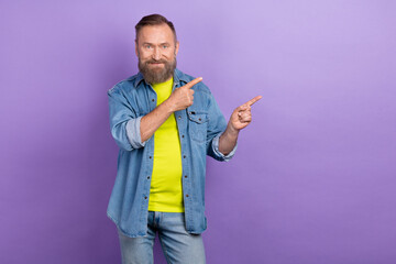 Portrait of positive aged person indicate fingers empty space proposition isolated on purple color background