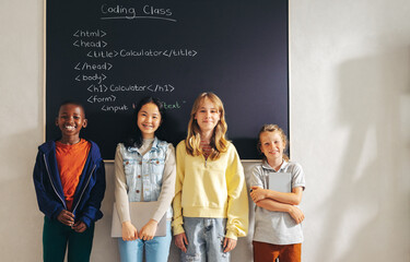 The next generation of coders: Group of young kids standing together in a coding classroom