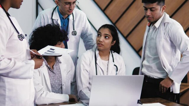 Medical indian students discussing  in a group. Science students doing  experimental project in the laboratory at university or library. High-skilled team of five young mixed race confident students