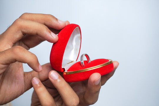 Man holding in his hands a red heart-shaped box with an engagement ring