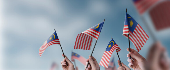 A group of people holding small flags of the Malaysia in their hands