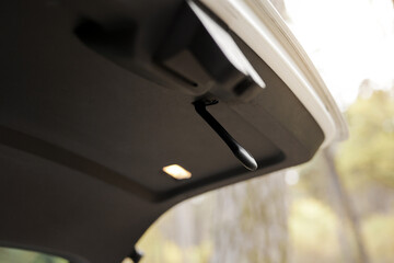 Trunk door handle. Modern white car trunk door opened. Vehicle outdoors in the park. Interior...