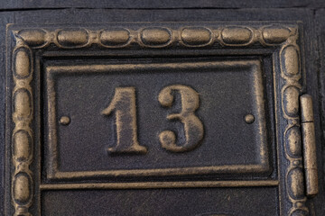 Number 13 on metal door. Old vintage retro copper plate with the number thirteen.