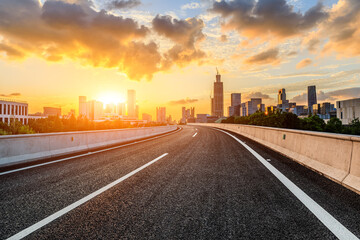 Asphalt road and modern city skyline with buildings at sunset in Ningbo, Zhejiang Province, China. 