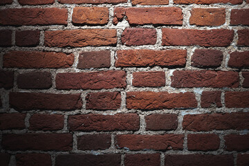 Grungy dark red brick wall with spotlight, background texture