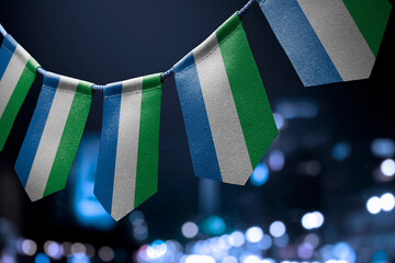 A garland of Sierra Leone national flags on an abstract blurred background - obrazy, fototapety, plakaty