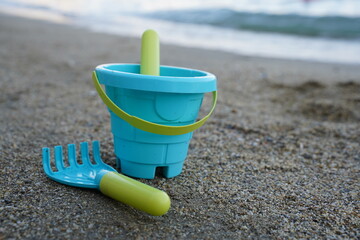 Children's beach toys, bucket, shovel and rake on the sand on a sunny day. The concept of summer holidays with children.