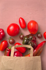 Layout of fresh red tomatoes and peppers. The vegetables are spilled out of a paper bag. Shopping Concept.