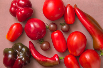 Layout of fresh red tomatoes and peppers. Pink background. Top view