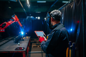 Engineer using robotic welder control panel.
