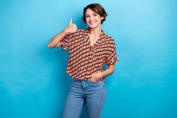 Obraz na płótnie Canvas Photo of cheerful nice girl toothy smile demonstrate thumb up isolated on blue color background