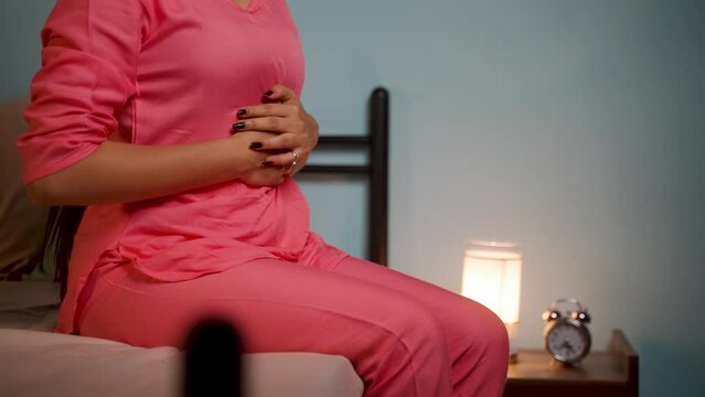 Close up shot of young girl suffering from stomach pain during night while sitting on sofa - concept of menstruation cycle, appendicitis and illens or unhealthy