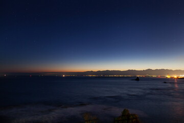 夜明けの空に残る星々と白波の富山湾