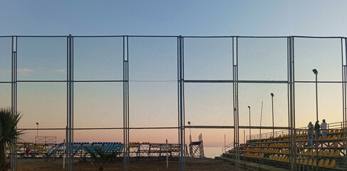 summer sunset shot through a basketball or football court and a playground. Sunset through a beach...