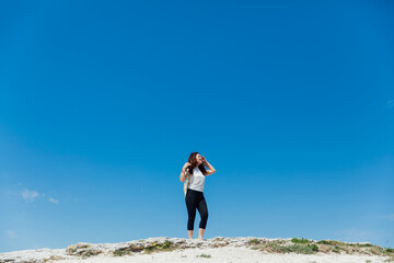 Obraz premium a woman standing on a mountain under a blue sky hiking journey