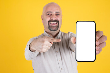 Holding smartphone, caucasian cheerful man holding smartphone. Showing empty blank white big screen cell phone to camera. Pointing display, recommending new app, web page, advertising, mock up idea.