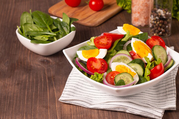 Appetizer healthy salad of fresh tomatoes, cucumber, spinach, lettuce and red onion. Vegan salad. Diet menu.