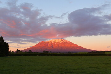 Fototapeta premium Sunrise with beautiful pink clouds at the stratovolcano Mt. Taranaki in the Egmont National Park of New Zealand