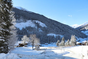an ice covered rural road and some farm houses in a mountain valley on a beautiful cold winter morning with fresh snow