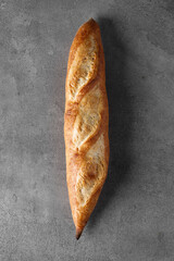 Rustic French sourdough baguette on a gray table, top view