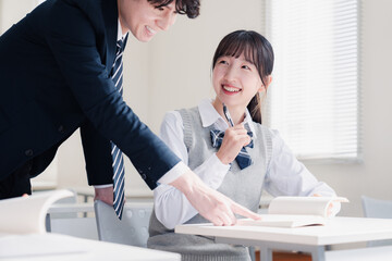 教室で先生に質問をする女子高生