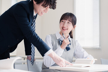 教室で先生に質問をする女子高生