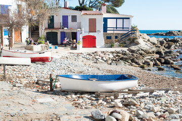 Fisherman town Cala s'Alguer, colorful huts, boats on the seashore. Surrounded with pine trees,...