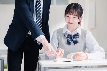 教室で先生に質問をする女子高生