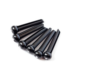 Pins for attaching acoustic guitar strings plastic black, filmed on a white background.