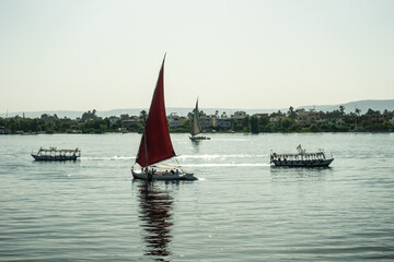 sailing boats and excursion boats against the light and at sunset. Boats on the Nile at Luxor Egypt