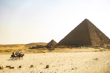 pyramids of giza in the sunlight with horsemen in the foreground. tourist attraction on the...