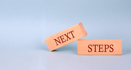 NEXT STEPS text on the wooden block, blue background
