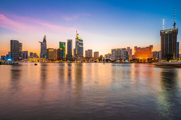 Fototapeta na wymiar Beautiful Sunset at Bitexco in Ho Chi Minh City, the famous building in Vietnam, with Vietnam flag on the top building. Colorful sky background. Travel concept