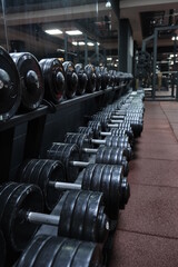 Athletic dumbbells in the gym. Sports equipment for strength exercises in weightlifting and bodybuilding. Set of muscle mass