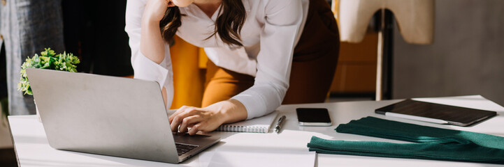 Fototapeta premium Fashion blogger concept, Young women selling clothes on video streaming.Startup small business SME, using smartphone or tablet taking receive and checking in studio