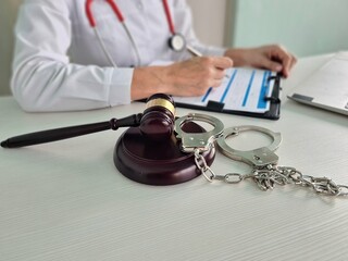 Judge gavel handcuffed doctor dealing with insurance paperwork in medical clinic