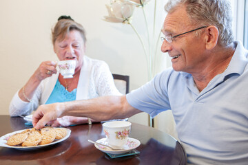 Retirement: Tea and Biscuits. A senior British couple sitting to enjoy a break and each others company. From a series of related images.